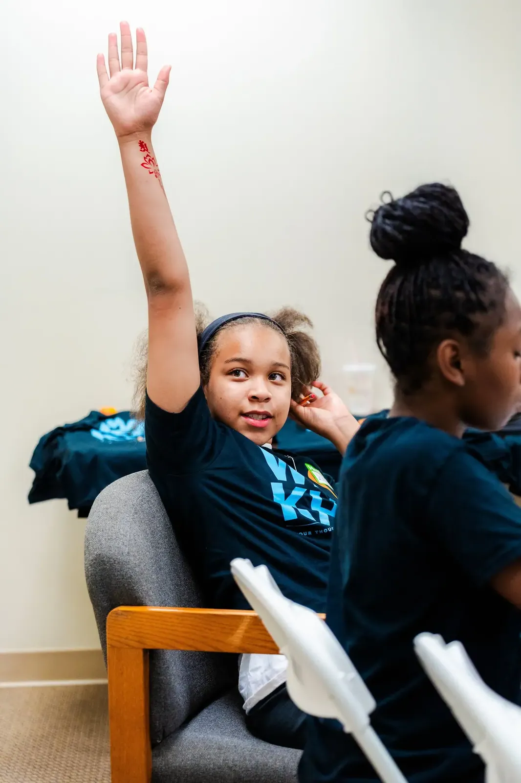 A smiling KHA youth raising her hand during a workshop