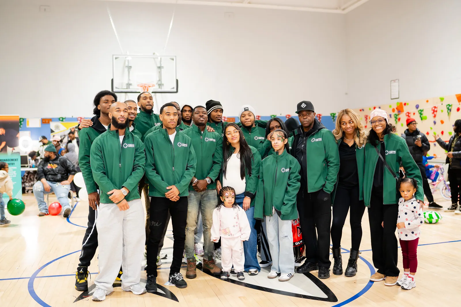 KHA staff in green jackets with families and volunteers at a community drive